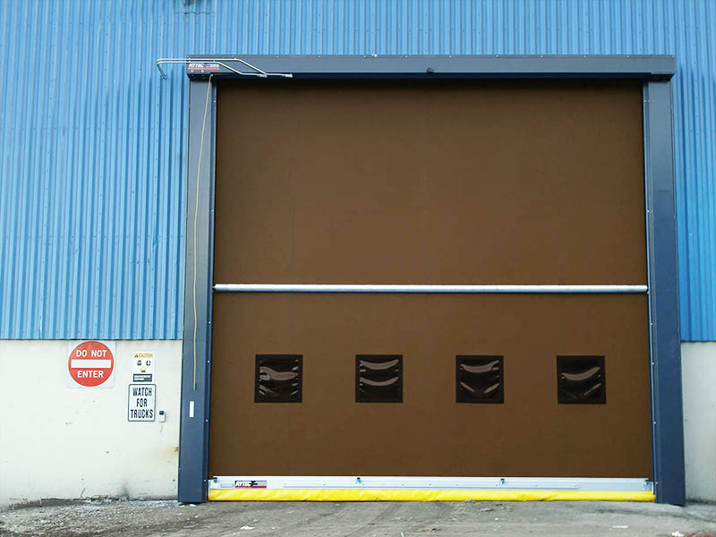 A red and white industrial roll-up door with the Rytec Fast Seal Manufacturing logo.