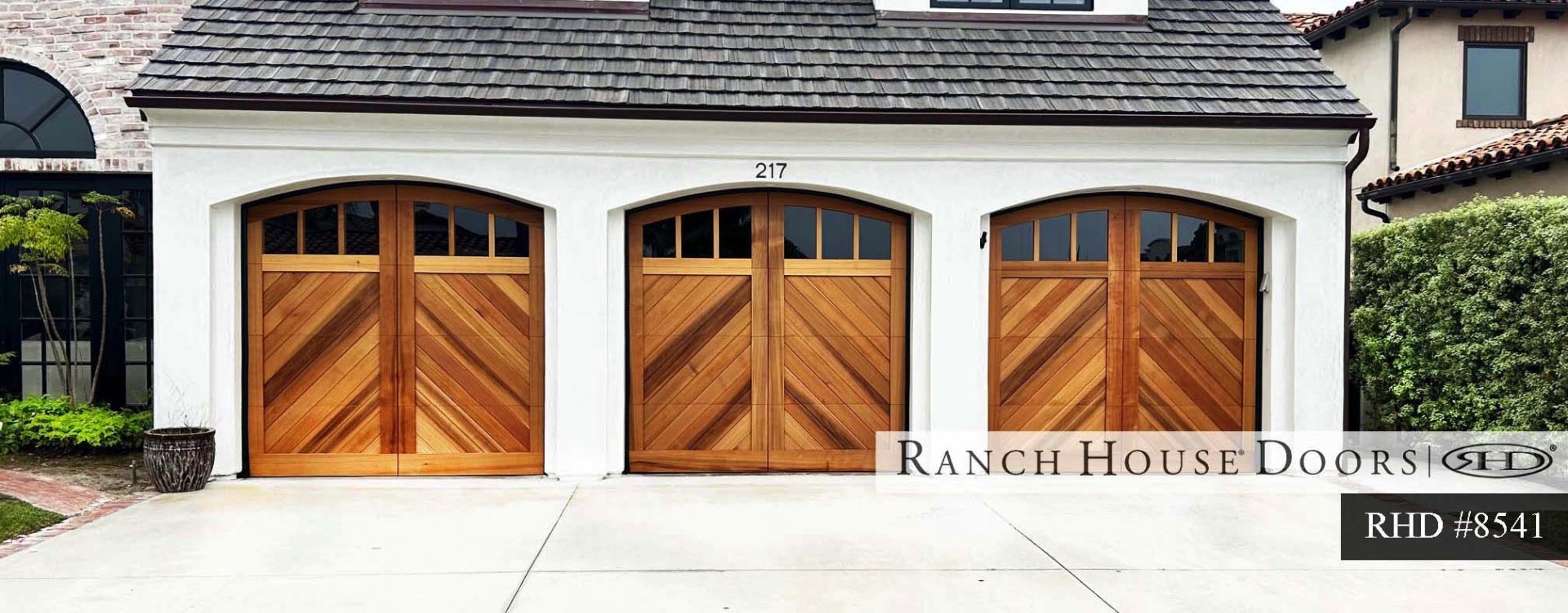 A traditional ranch house with a carriage style garage door in a suburban neighborhood.
